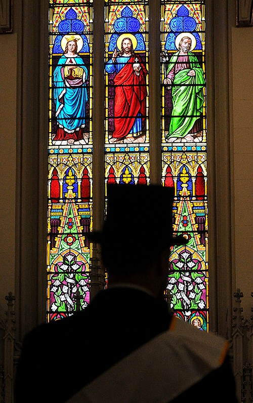 Silhouetted by the north window at St. Joseph Cathedral, a topped hat St. Patrick's Day Parade Marshall prepares to receive Holy Communion during the St. Patrick's Day Mass. (Dan Cappellazzo/Staff Photographer)